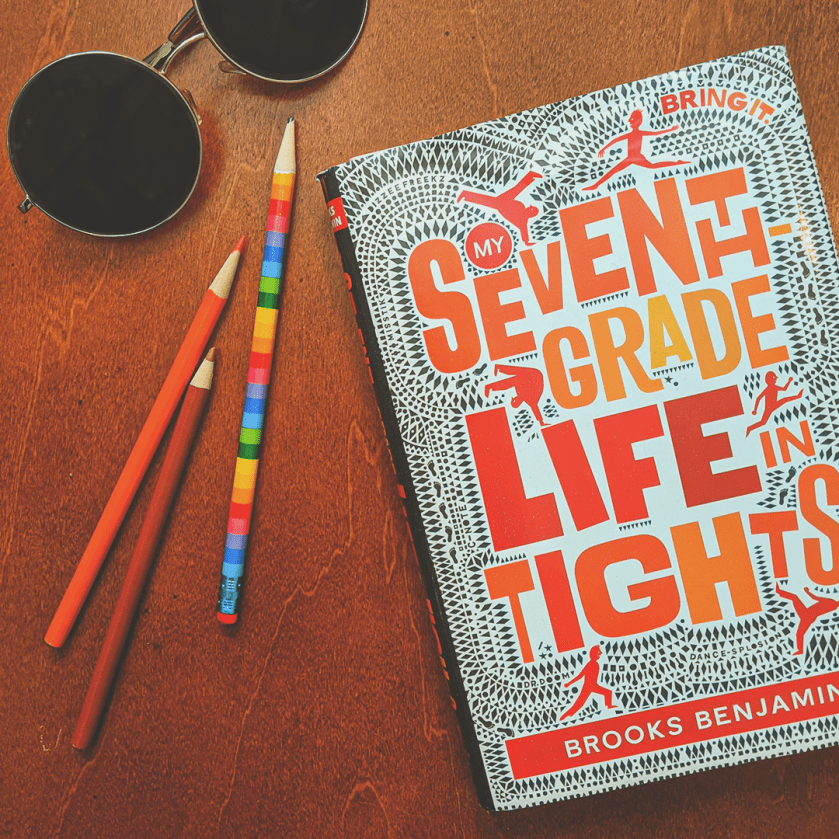 Bookstagram photo features My Seventh-Grade Life in Tights by Brooks Benjamin. A pair of sunglasses and some colorful pencils are gathered on the table next to the book.