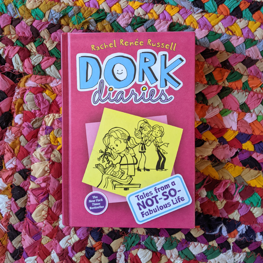 Bookstagram photo feature DORK DIARIES: TALES FROM A NOT-SO-FABULOUS LIFE by Rachel Renee Russell laying on a colorful braided rug.