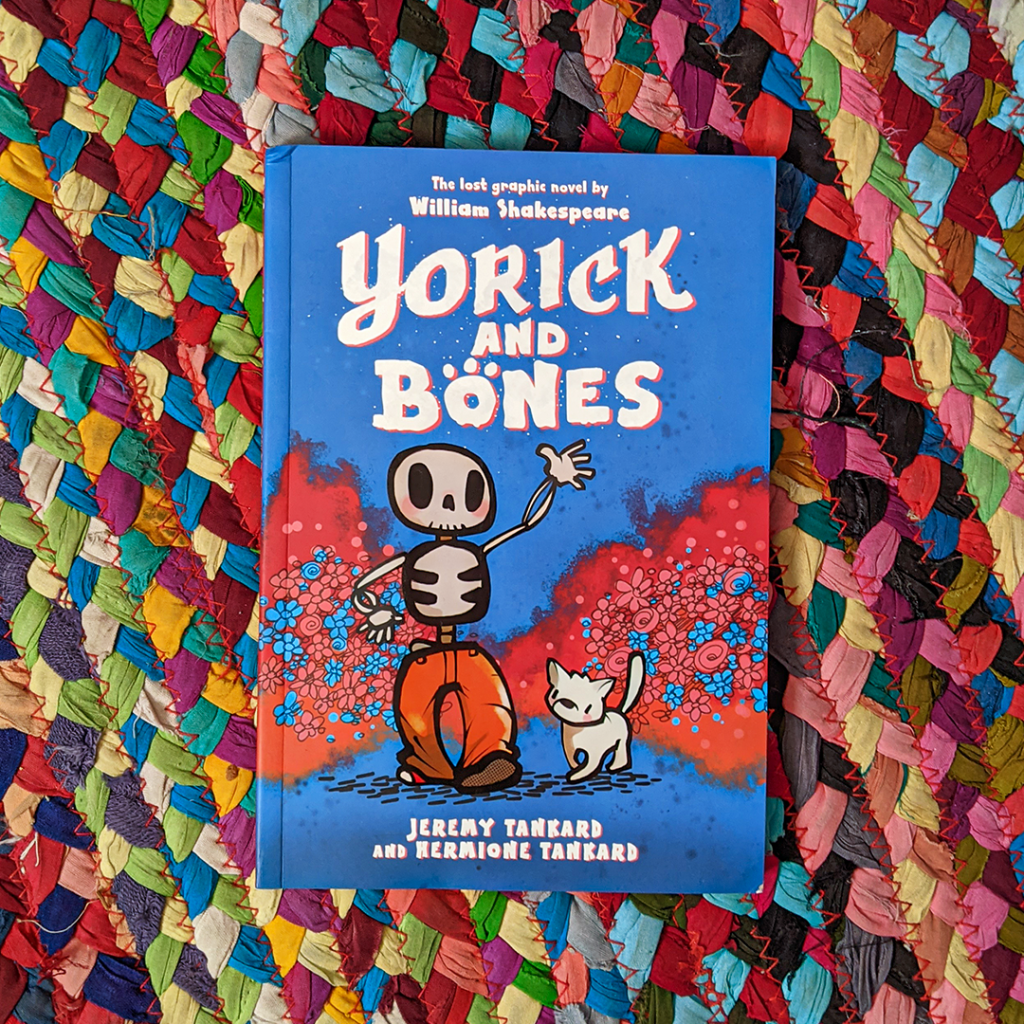 Photograph features the book YORICK AND BONES which lays on a colorful braided rug.